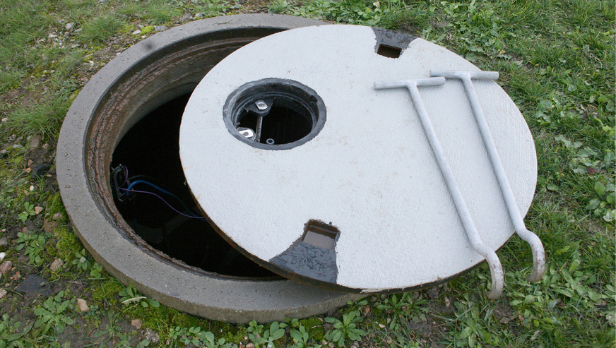 ﻿Unterirdischer Regenwasser­speicher nach Einbau im ­Gelände, hier mit Abdeckung inkl. Einsatzdeckel für Bewässerungssystem Fontana M, das durch die ­kleine Öffnung mit Gartenschlauch ­manuell in Betrieb genommen wird. Die große Abdeckung wird nur gelegentlich zur Filterreinigung entfernt.