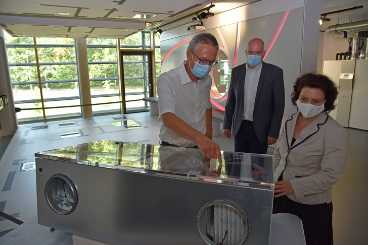 Geschäftsführer Dr. Kai Schiefelbein (links) mit Ministerin Dr. Carola Reimann am Lüftungsgerät, das speziell für den Einsatz in Klassenzimmern entwickelt wurde. Im Hintergrund Burkhard Max, Geschäftsführer der Stiebel Eltron-Tochtergesellschaft Tecalor, die das Gerät vertreibt. - © Stiebel Eltron
