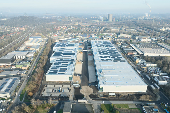 Alt-Text: „Luftaufnahme eines weitläufigen Sanitär-, Heizungs- und Klimatechnik-Betriebsgeländes mit Solarmodulen auf den Dächern, eingebettet in ein Netzwerk aus Straßen und Grünflächen, als Sinnbild für nachhaltige Energieerzeugung und moderne Infrastruktur in der SHK-Branche. - © Mitsubishi Electric / Philip Kistner