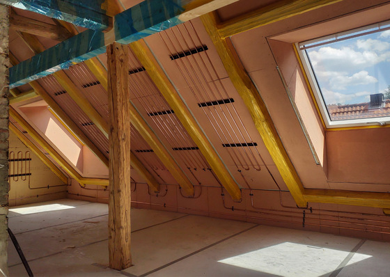 Gerne! Hier ein optimierter, fachgerechter Alt-Text für das Bild im Kontext der SHK-Branche: Alt-Text: Dachgeschoss im Ausbau mit freiliegenden Holzbalken, sichtbaren Elektroinstallationen und großflächigen Dachfenstern zur Tageslichtnutzung; Darstellung moderner Installationstechnik während der Bauphase. Begründung: Der neue Text beschreibt nicht nur die sichtbaren Elemente, sondern betet sie in den thematischen Kontext (Installationsphase, moderne Gebäudetechnik) ein. Dadurch werden Fachkräfte gezielt angesprochen und Informationen wie Materialeinsatz sowie Tageslichtaspekt berücksichtigt. Bei Bedarf kann er noch spezifischer ausgestaltet werden – etwa mit Erwähnungen zu Wärmedämmung oder vorbereitender Heizungsinstallation, fällt dies visuell erkennbar ist. - © Bild: Forum Wohnenergie