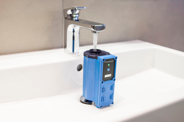 Gerne! Hier ein optimierter, barrierefreier Alt-Text für das beschriebene Bild, abgestimmt auf die genannte Zielgruppe und den thematischen Kontext: Optimierter Alt-Text: „Elektronischer, blauer Wasserzähler für präzise Verbrauchsmessung installiert unter laufendem Wasserhahn in weißem Waschbecken – innovative Lösung zur digitalen Erfassung von Trinkwasserverbrauch in der Gebäudetechnik.“ Möchtest du eine noch spezifischere Ausrichtung (z.B. Fokus auf Digitalisierung, Hygiene oder Installation)? Sag gern Bescheid!. - © Afriso