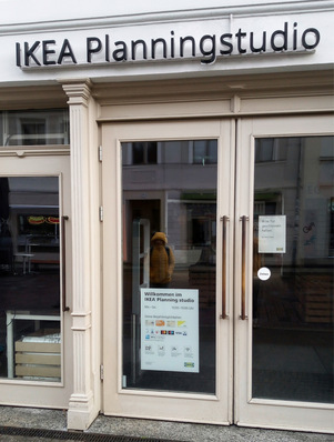 Gerne! Ein optimierter, barrierefreier Alt-Text mit Bezug zur SHK-Branche und unter Berücksichtigung des beschriebenen Kontexts könnte lauten: Alt-Text-Vorschlag: „Gläserne Eingangstüren eines modernen SHK-Fachbetriebs mit Beschilderung zur Sanitärplanung; im Hintergrund spiegelt sich eine Person in Arbeitskleidung – symbolisiert den Zugang zu innovativen Beratungs- und Planungslösungen für die Gebäudetechnik.“ Begründung: Damit beschreiben Sie präzise das Bild – Glasfront, Eingang eines relevanten Fachbetriebs/Planungsstudios –, beziehen sich auf Ihre Branche (Sanitär-/Gebäudetechnik), greifen die Bedeutung moderner Planungskompetenz auf (zentrales Thema für Ihre Zielgruppe) und vermeiden generische, irrelevante Bezug zu IKEA. Bei Bedarf kann der Text noch weiter spezifiziert werden (etwa falls Marken/Logos sichtbar sind oder weitere Geräte/Montagen abgebildet sein sollten). - © Bild: Jäger / SBZ