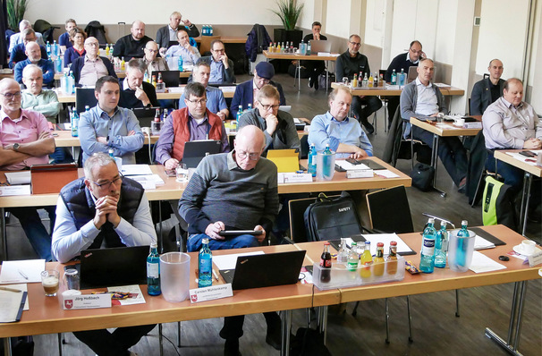 Menschen, die an Tischen in einem Konferenzraum sitzen, aufmerksam mit Laptops, Getränken und Papieren vor sich. - © Bild: SBZ / Dietrich