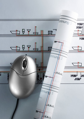 Eine Computermaus und ein gerollter Bauplan auf einer technischen Zeichnung. - © Bild: Viega