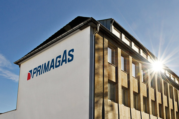 Bürogebäude mit "PRIMAGAS"-Logo an der Wand, die Sonne scheint an der Ecke unter einem klaren blauen Himmel. - © Primagas