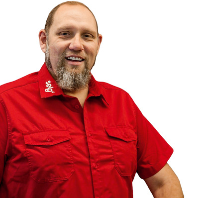 Lächelnder Mann mit Bart, der ein rotes Hemd mit der Aufschrift "Selby" am Kragen trägt und vor einem weißen Hintergrund steht. - © Bild: Selg